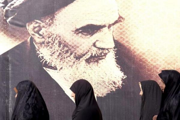 Wanita Iran berjalan melewati poster mendiang pemimpin Iran Ayatollah Ruhollah Khomeini di selatan Teheran (Foto: Reuters) 