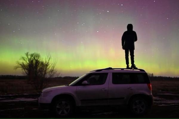 Seseorang berdiri di atas mobil sambil melihat Aurora di wilayah barat daya Siberia Omsk, Rusia 6 November 2023. Foto: Reuters 