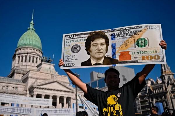 Seorang pendukung Presiden Argentina Javier Milei memperlihatkan plakat uang $100 bergambar pemimpinnya. (FOTO: AFP)