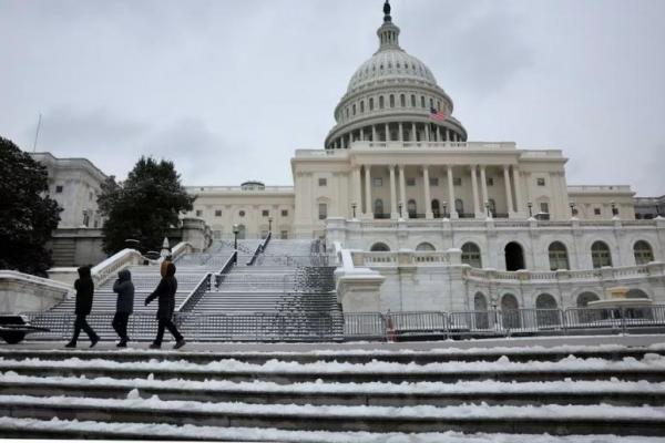 Orang-orang berjalan melewati gedung US Capitol yang bersalju di Washington, AS, 16 Januari 2024. Foto: Reuters 