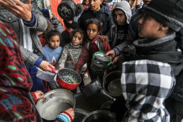 Warga Palestina yang memegang mangkuk kosong menerima makanan yang didistribusikan oleh relawan badan amal saat masyarakat menghadapi krisis kelaparan dan risiko kelaparan akibat embargo Israel yang diberlakukan di Gaza. (FOTO: ANADOLU AGENCY)