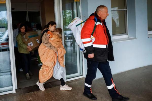 Seorang wanita dengan bayi meninggalkan rumah sakit setelah otoritas setempat menyatakan bahwa ada kemungkinan bahaya serangan militer Rusia, di Kyiv, Ukraina, 26 April 2024. REUTERS 