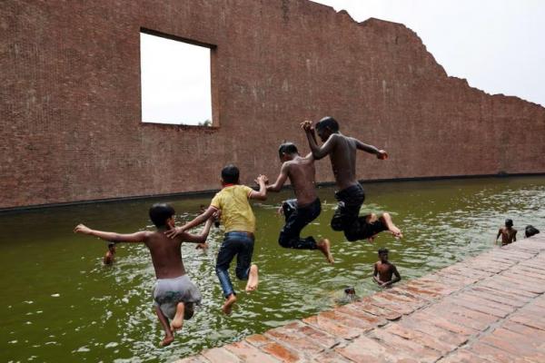 Anak-anak melompat ke perairan Martyred Intellectuals Memorial di Rayerbazar, untuk mendinginkan diri saat gelombang panas di Dhaka, Bangladesh, 23 April 2024. REUTERS 