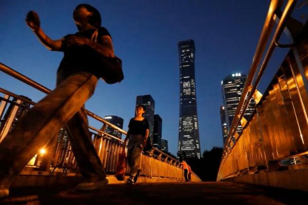Pejalan kaki berjalan di jembatan layang dekat gedung pencakar langit di Kawasan Pusat Bisnis di Beijing, 21 Agustus 2023. REUTERS 
