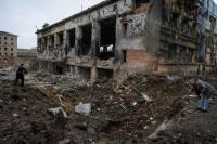 Para ahli memeriksa kawah di sebelah bangunan yang rusak berat akibat serangan rudal Rusia, di pusat Kharkiv, Ukraina 2 Januari 2024. REUTERS