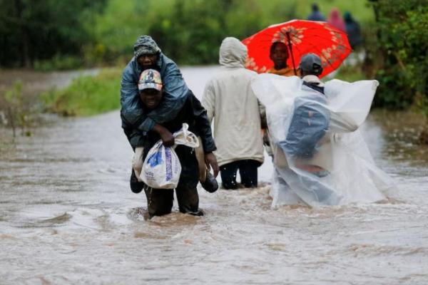 Warga menyeberangi air banjir setelah sungai musiman meluap akibat hujan deras di kota Kitengela, Kabupaten Kajiado, dekat Nairobi, Kenya 1 Mei 2024. REUTERS 