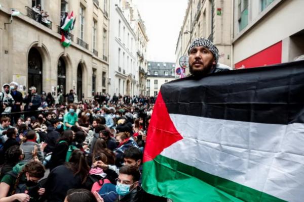 Seseorang memegang bendera Palestina ketika pengunjuk rasa menduduki jalan di depan gedung Sciences Po untuk mendukung warga Palestina di Gaza. (FOTO: REUTERS) 