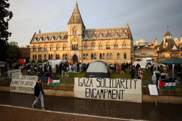 Seorang wanita berjalan di dekat tenda di Universitas Oxford, ketika para mahasiswa protes mendukung warga Palestina di Gaza, di Oxford, Inggris, 6 Mei 2024. REUTERS 