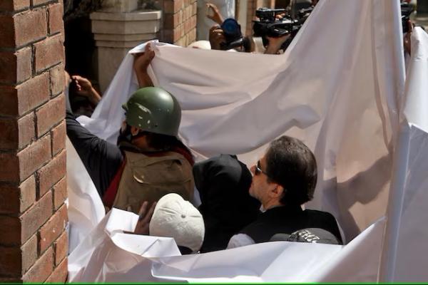 Mantan Perdana Menteri Pakistan Imran Khan dan istrinya Bushra Bibi ditutupi kain putih saat mereka tiba di Pengadilan Tinggi di Lahore, Pakistan, 15 Mei 2023. REUTERS 