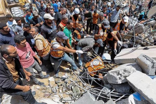 Orang-orang bekerja untuk menemukan mayat seorang warga Palestina yang terperangkap di bawah reruntuhan, di kamp pengungsi Nuseirat di pusat Jalur Gaza, 14 Mei 2024. REUTERS 