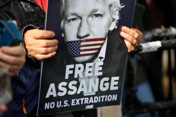 Seorang pendukung Julian Assange memegang pamflet di London, Inggris, 26 Maret 2024. REUTERS 
