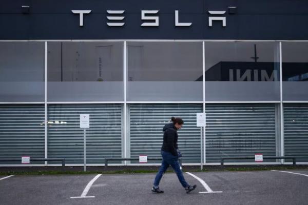Seorang wanita berjalan di depan dealer Tesla di Saint-Herblain dekat Nantes, Prancis, 25 Maret 2025. (REUTERS) 