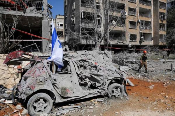 Seorang penyelamat berjalan di samping kendaraan yang rusak di lokasi jatuhnya pesawat setelah serangan rudal dari Iran ke Israel, di Ramat Gan, Israel, 14 Juni 2025. REUTERS 