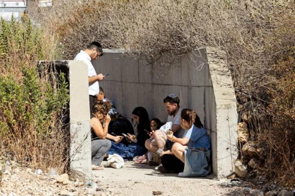 Warga Israel berlindung di sisi jalan raya saat sirene berbunyi menyusul serangan rudal dari Iran di Israel, di Israel tengah 15 Juni 2025. REUTERS 