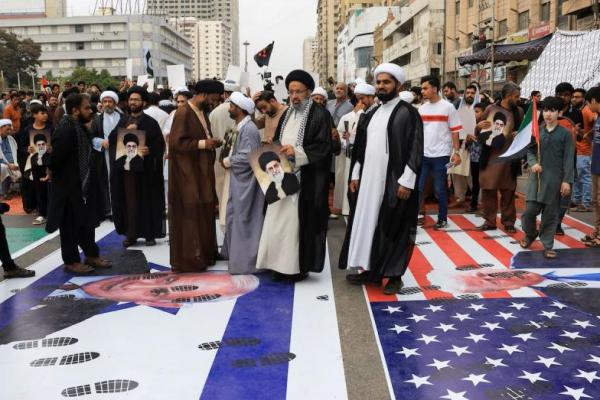 Muslim Syiah Pakistan berjalan di atas poster yang menggambarkan bendera Israel dan AS dalam unjuk rasa tolak Israel, di Karachi, Pakistan, 22 Juni 2025. REUTERS 
