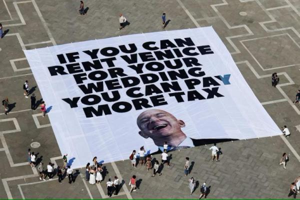 Spanduk besar yang menentang pendiri Amazon Jeff Bezos tergeletak di tanah, dipasang oleh aktivis Greenpeace Italia di Lapangan Santo Markus, jelang pernikahan Jeff Bezos dan Lauren Sanchez, di Venesia, Italia, 23 Juni 2025. REUTERS 