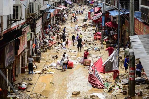 Orang-orang berjalan sambil membawa barang-barang mereka di daerah yang terkena banjir di Congjiang, provinsi Guizhou, Tiongkok barat daya. (FOTO: AFP) 