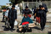 Seorang pria mendorong seorang wanita tua di troli bagasi bandara di Pangkalan Udara Hmeimim, di Latakia, Suriah barat, 20 Maret 2025. REUTERS