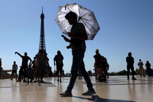 Seorang turis memegang payung untuk melindungi dirinya dari matahari saat berjalan di alun-alun Trocadero di sebelah Menara Eiffel di Paris, Prancis, 1 Juli 2025. REUTERS 