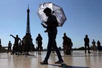 Seorang turis memegang payung untuk melindungi dirinya dari matahari saat berjalan di alun-alun Trocadero di sebelah Menara Eiffel di Paris, Prancis, 1 Juli 2025. REUTERS