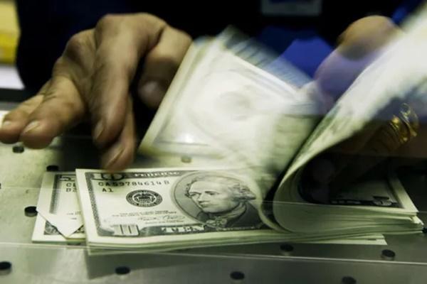 Seorang kasir di Bursa Mata Uang Travelex menghitung Dolar AS yang ditukar dengan Poundsterling Inggris. (FOTO: GETTY IMAGE) 