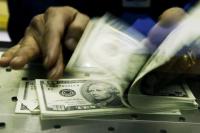 Seorang kasir di Bursa Mata Uang Travelex menghitung Dolar AS yang ditukar dengan Poundsterling Inggris. (FOTO: GETTY IMAGE)