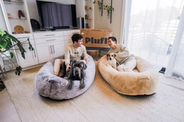 Pendiri Plufl Noah Silverman dan Yuki Kinoshita berpose dengan tempat tidur anjing-manusia buatan China di lokasi yang tidak disebutkan. Handout via REUTERS 