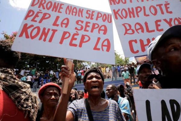 Seorang perempuan memegang spanduk bertuliskan dalam bahasa Kreol Haiti: Drone untuk rakyat, bukan melawan rakyat, saat protes menentang ketidakamanan, di Port-au-Prince, Haiti, 28 Juni 2025. REUTERS 