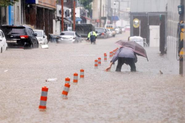 Seorang pria berjalan melewati jalan yang terendam banjir akibat hujan deras di Gwangju, Korea Selatan, 17 Juli 2025. Yonhap via REUTERS 
