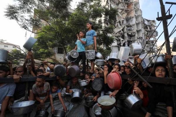 Warga Palestina menunggu untuk menerima makanan dari dapur amal, di tengah krisis kelaparan, di Kota Gaza. REUTERS 