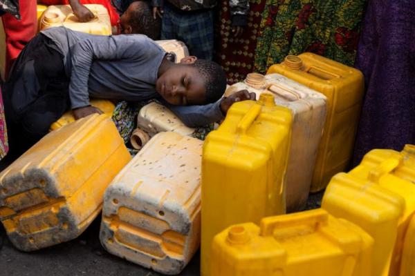 Seorang anak tidur di atas jerigen plastik sementara orang-orang mengantre di pipa air minum, di Goma, provinsi Kivu Utara, Republik Demokratik Kongo, 16 Juni 2025. REUTERS 