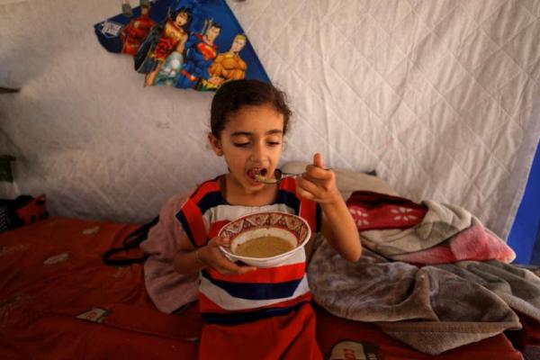 Eyala, putri seorang pengungsi Palestina, Nizar Bakron, makan di dalam tenda mereka, di Kota Gaza, 17 Juli 2025. REUTERS 