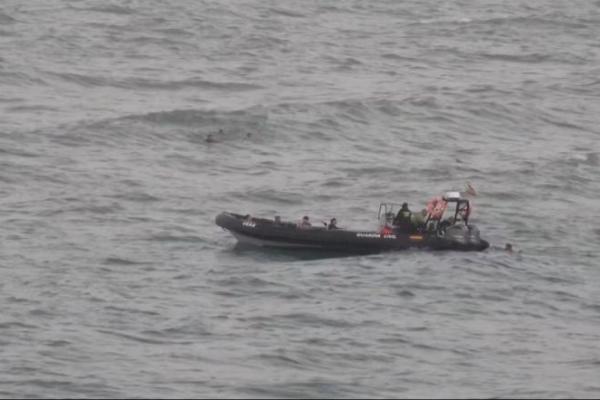 Sebuah pemandangan menunjukkan para migran mencapai perahu polisi, sementara sekelompok migran lainnya berenang di latar belakang, di Afrika Utara, Ceuta, di Ceuta, Spanyol, 25 Juli 2025. Handout via REUTERS 