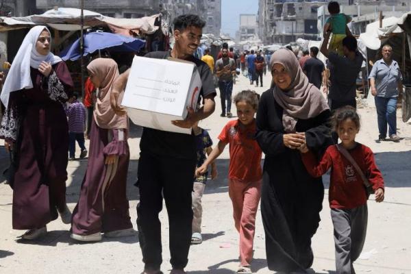 Putra perempuan Palestina yang terlantar, Iman Suleiman, dari Beit Lahiya, membawa kotak bantuan yang diterima keluarganya, di Kota Gaza, 26 Juni 2025. REUTERS 