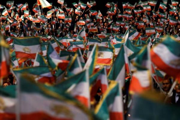 Orang-orang mengibarkan bendera dalam sebuah acara di kamp Ashraf-3, yang merupakan markas Organisasi Mujahidin Rakyat Iran atau MEK di Manza, Albania, 13 Juli 2019. REUTERS 