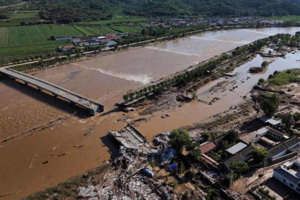 Pemandangan drone menunjukkan jalan yang rusak dan pohon tumbang di samping Sungai Qingshui yang meluap di distrik Miyun, Beijing, Tiongkok, 29 Juli 2025. REUTERS 
