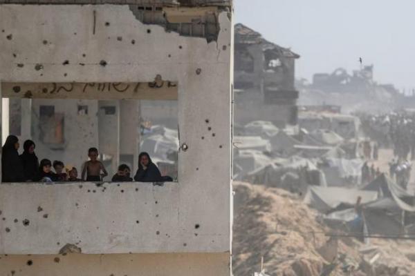Perempuan dan anak-anak melihat keluar dari bangunan yang rusak saat warga Palestina membawa pasokan bantuan yang masuk ke Gaza melalui Israel, di Beit Lahia, Jalur Gaza utara, 2 Agustus 2025. REUTERS 
