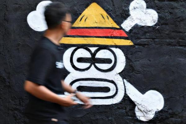 Kemas Muhammad Firdaus, 28, berjalan melewati mural yang menggambarkan Jolly Roger dari serial anime dan manga populer Jepang One Piece di Bekasi, provinsi Jawa Barat, Indonesia, 7 Agustus 2025. REUTERS 