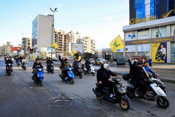 Para pria membawa bendera Hizbullah sambil mengendarai kendaraan roda dua, di pintu masuk pinggiran selatan Beirut, Lebanon, 27 November 2024. REUTERS 