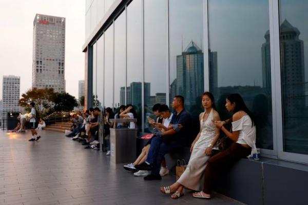 Orang-orang beristirahat di teras pusat perbelanjaan saat matahari terbenam, di kawasan pusat bisnis Beijing, Tiongkok, 11 Agustus 2025. REUTERS 