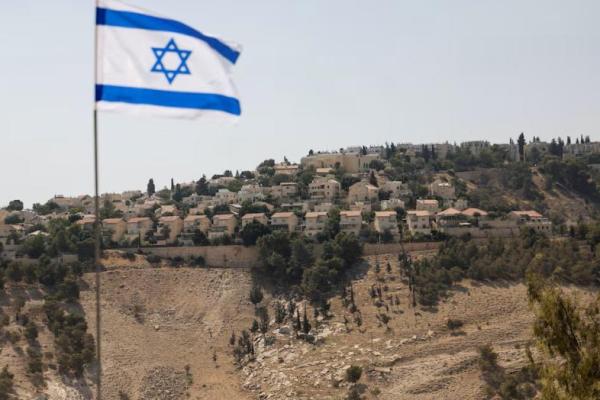 Bendera Israel berkibar dengan latar belakang permukiman Israel Maale Adumim di Tepi Barat yang diduduki Israel, 14 Agustus 2025. REUTERS 