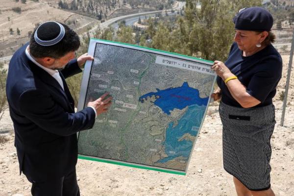 Menteri Keuangan Israel Bezalel Smotrich dan seorang perempuan memegang peta permukiman E1 pada hari konferensi pers di dekat permukiman Israel Maale Adumim, di Tepi Barat yang diduduki Israel, 14 Agustus 2025. REUTERS 