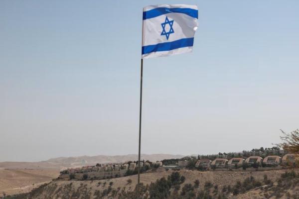 Bendera Israel berkibar, sementara sebagian permukiman Israel di Maale Adumim terlihat di latar belakang, di Tepi Barat yang diduduki Israel, 14 Agustus 2025. REUTERS 