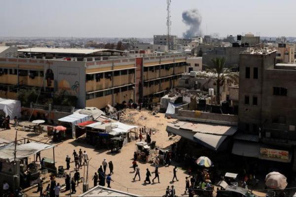 Warga Palestina berjalan di tengah asap mengepul di kejauhan, menyusul serangan Israel, di Khan Younis, Jalur Gaza selatan, 14 Agustus 2025. REUTERS 