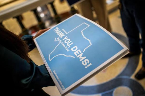 Seorang pria memegang spanduk dan pengunjuk rasa berbaris di area dekat ruang sidang DPR memprotes perubahan distrik, di Austin, Texas, AS, 18 Agustus 2025. REUTERS 