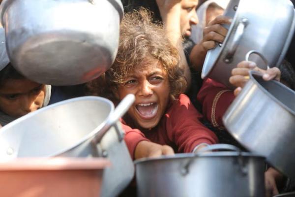 Seorang anak bereaksi dikelilingi panci saat warga Palestina menunggu menerima makanan dari dapur amal di Khan Younis, Jalur Gaza selatan, 21 Agustus 2025. REUTERS 