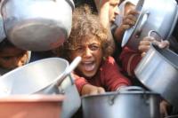 Seorang anak bereaksi dikelilingi panci saat warga Palestina menunggu menerima makanan dari dapur amal di Khan Younis, Jalur Gaza selatan, 21 Agustus 2025. REUTERS