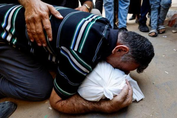 Seorang ayah Palestina, Mahmoud Abedrabo, berduka atas jenazah putranya, Hamada, yang tewas dalam serangan Israel, di Rumah Sakit Al-Shifa di Kota Gaza, 24 Agustus 2025. REUTERS 