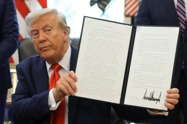 Presiden AS Donald Trump mengangkat perintah eksekutif setelah menandatanganinya di Ruang Oval Gedung Putih di Washington, AS, 25 Agustus 2025. REUTERS 