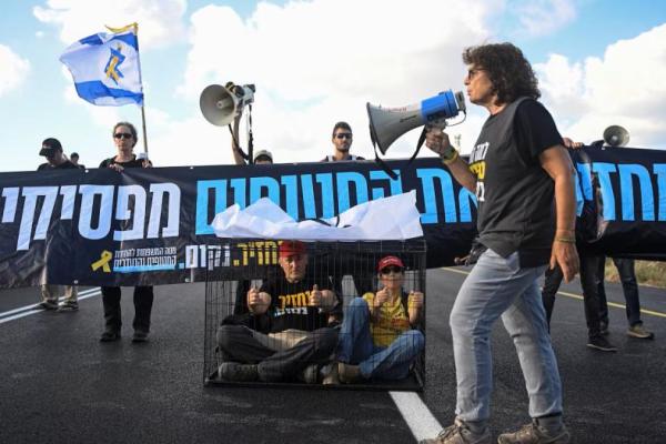 Para pengunjuk rasa duduk di dalam sangkar saat mereka memblokir jalan menuntut diakhirinya segera perang dan pembebasan semua sandera, dekat Habonim, Israel, 26 Agustus 2025. REUTERS 